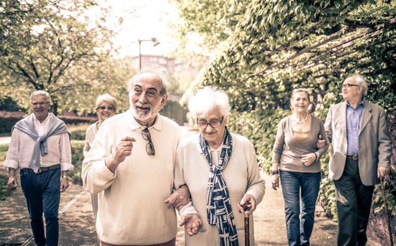 Eine Gruppe von Seniorinnen und Senioren gehen im Freien spazieren 