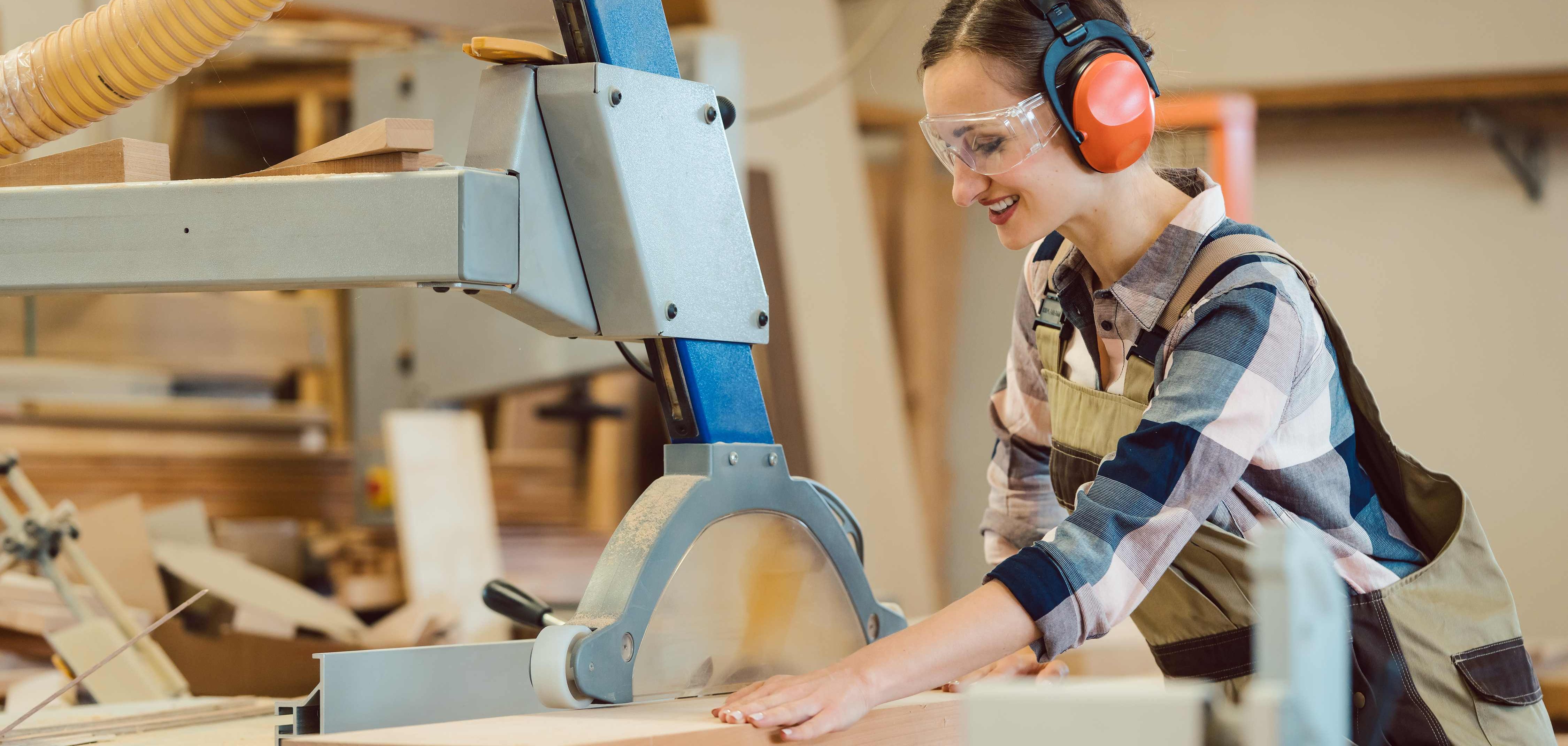 Eine junge, dunkelhaarige Frau arbeitet an einer Kreissäge.