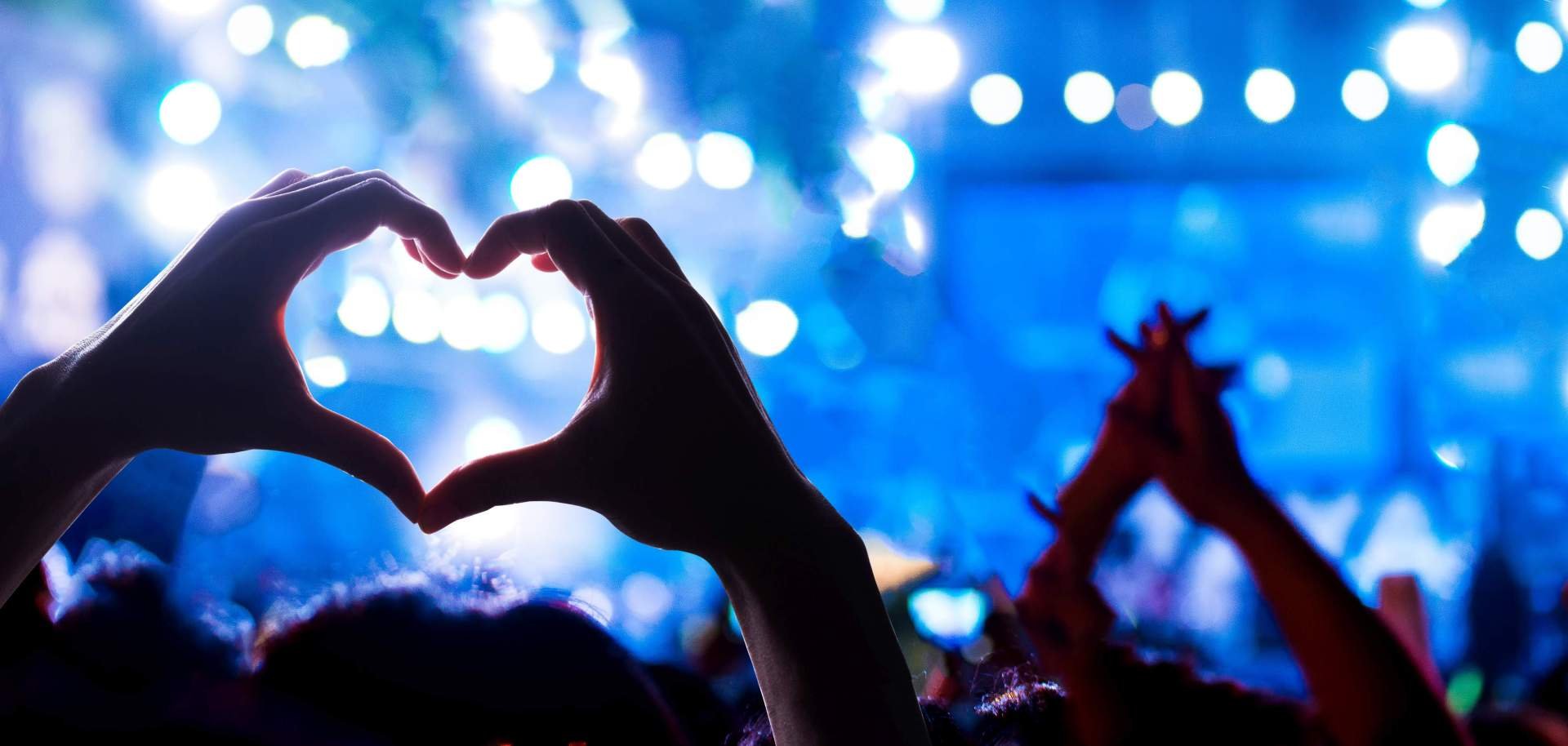 Ein Konzert, bei dem ein Zuschauer ein Herz mit den Händen formt.