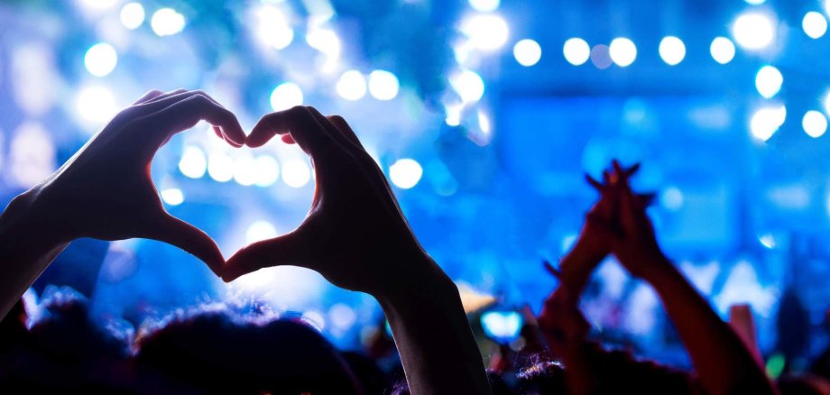 KUSS Bewerbungsfrist Ein Konzert, bei dem ein Zuschauer ein Herz mit den Händen formt.