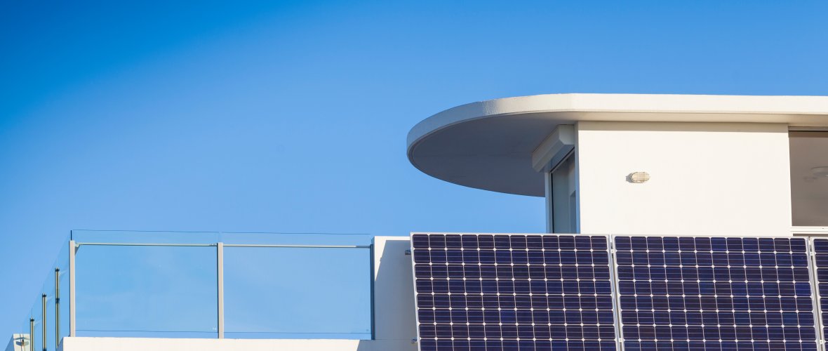 Ein Photovoltaik-Modul ist an einem weißen Hausbalkon angebracht.