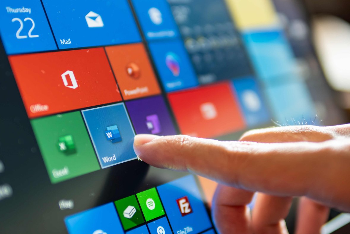 Microsoft Oberfläche Ein Tablet, auf dem das Kachelinterface von Microsoft zu sehen ist. Ein Finger berührt die Kachel von Microsoft Word.