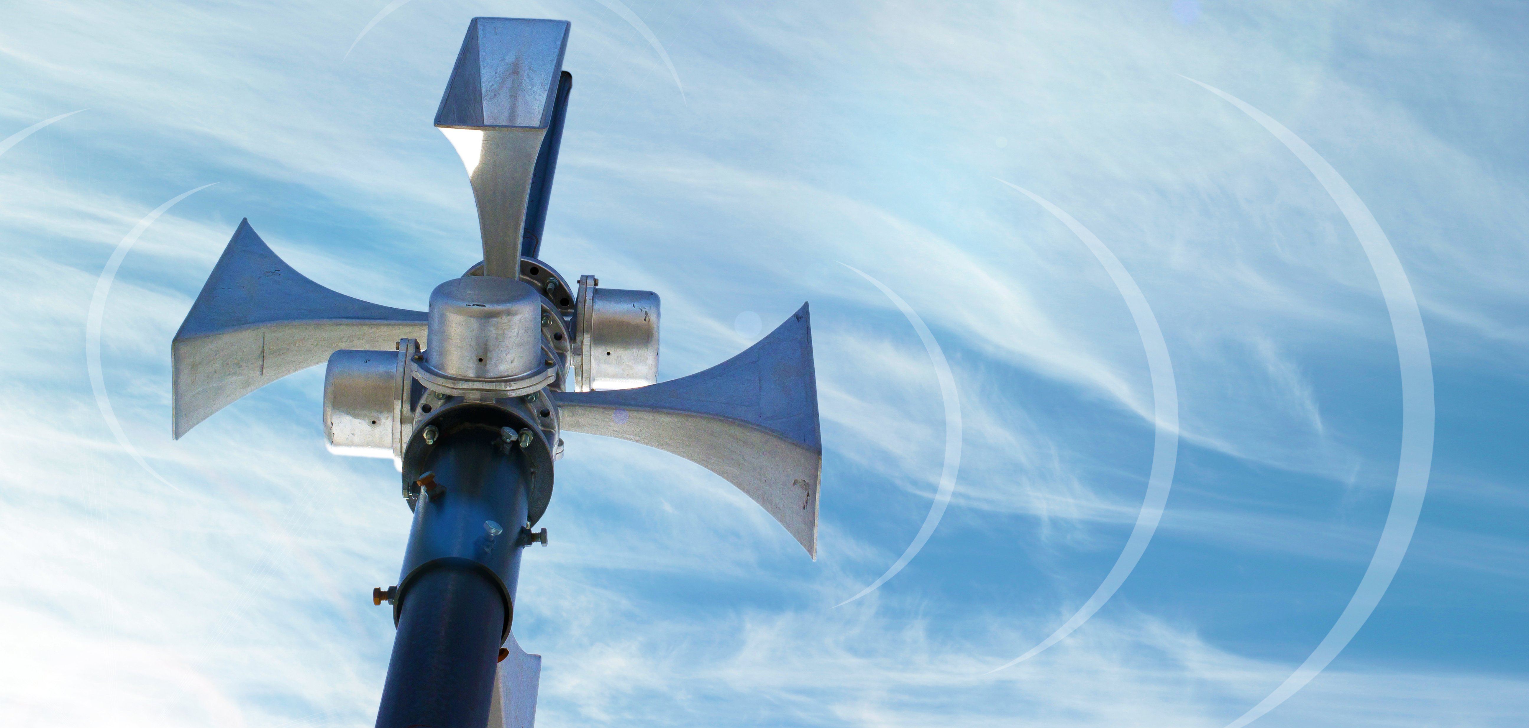 Eine Sirene steht unter dem blauen Himmel, von ihr gehen Soundwellen aus.