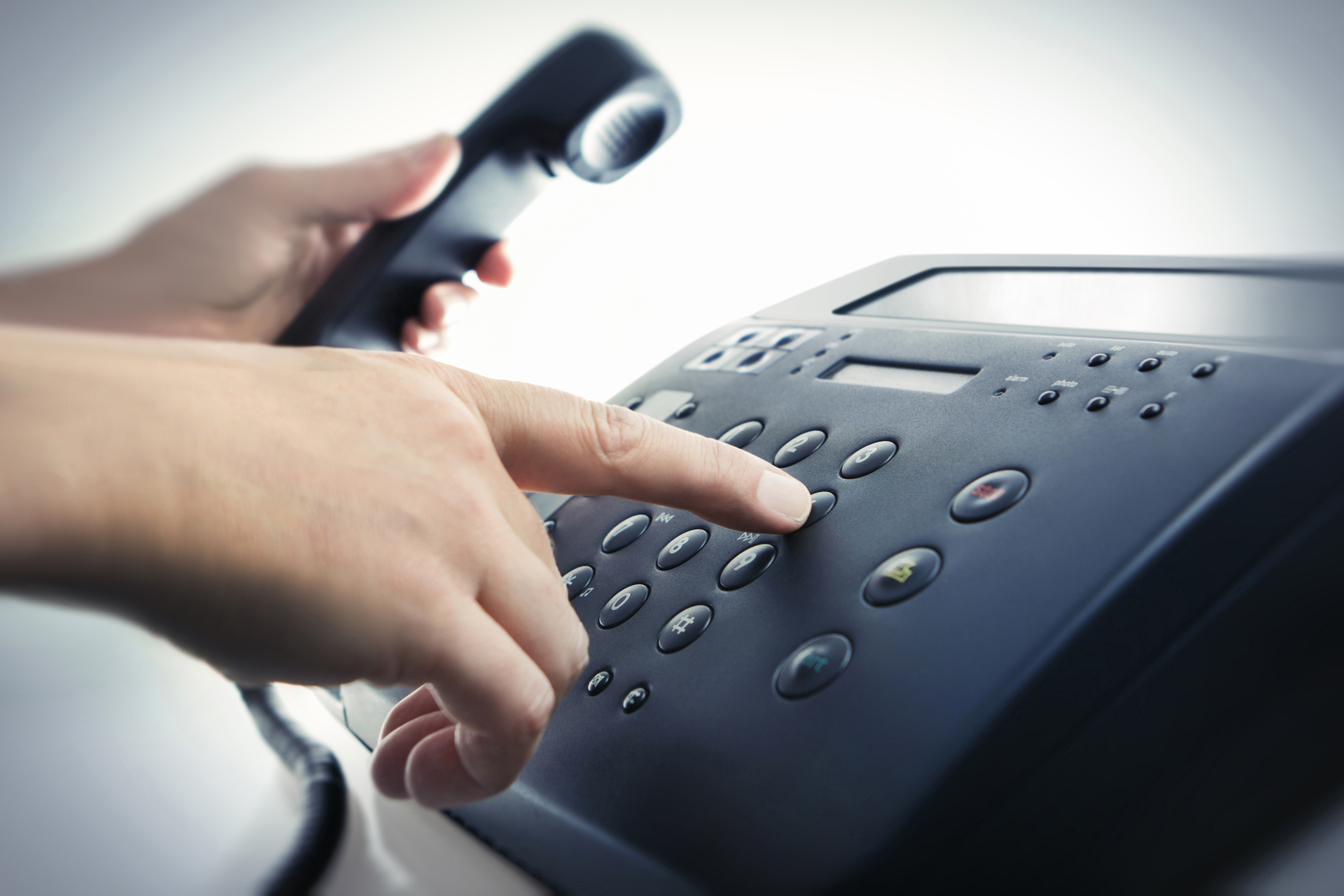 Männliche Hand wählt eine Nummer am Telefon und hat den Hörer in der Hand