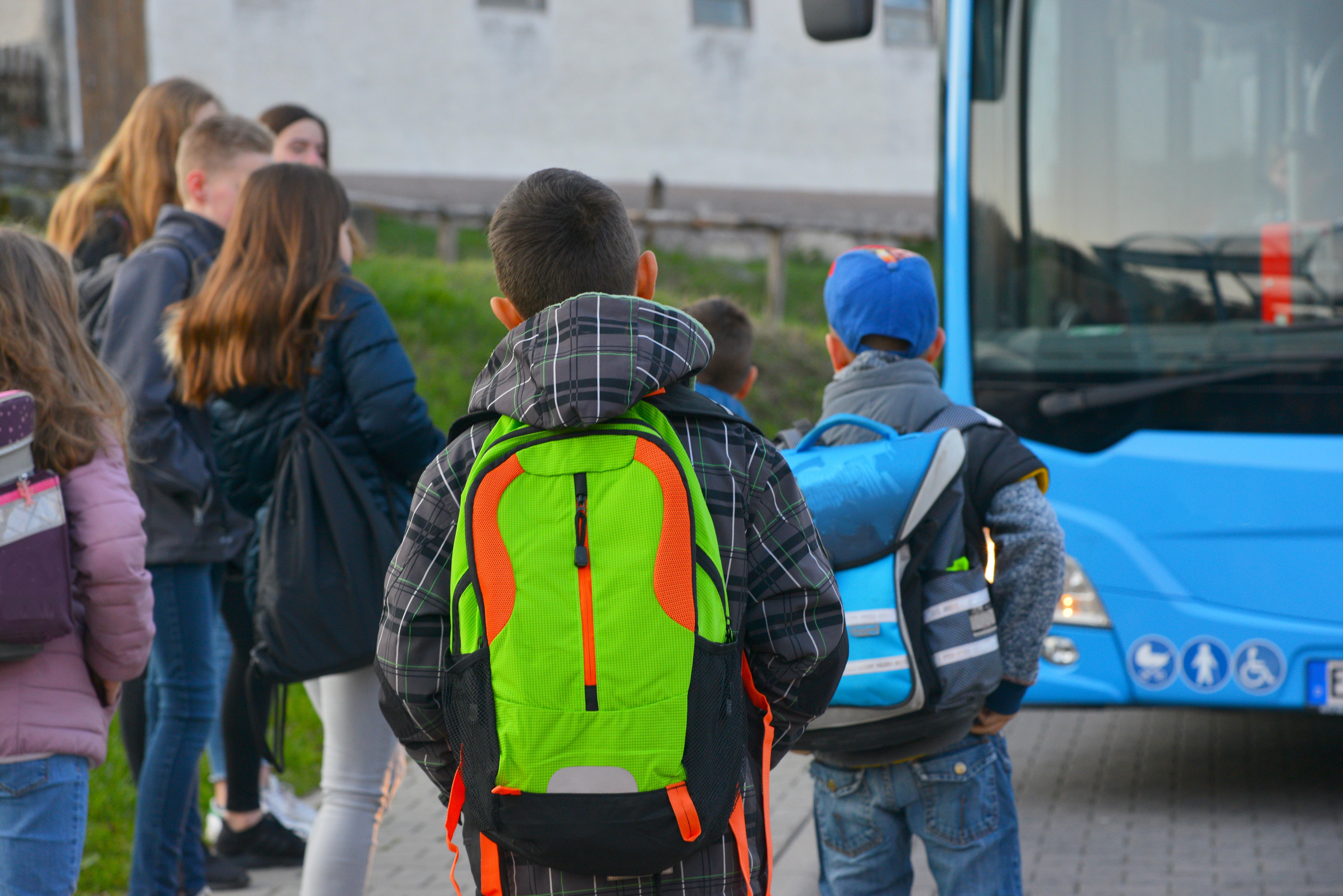 Das Symbolbild zeigt Schüler mit Schulrucksack der Grundschule auf dem morgendlichen Weg zum Schulbus.