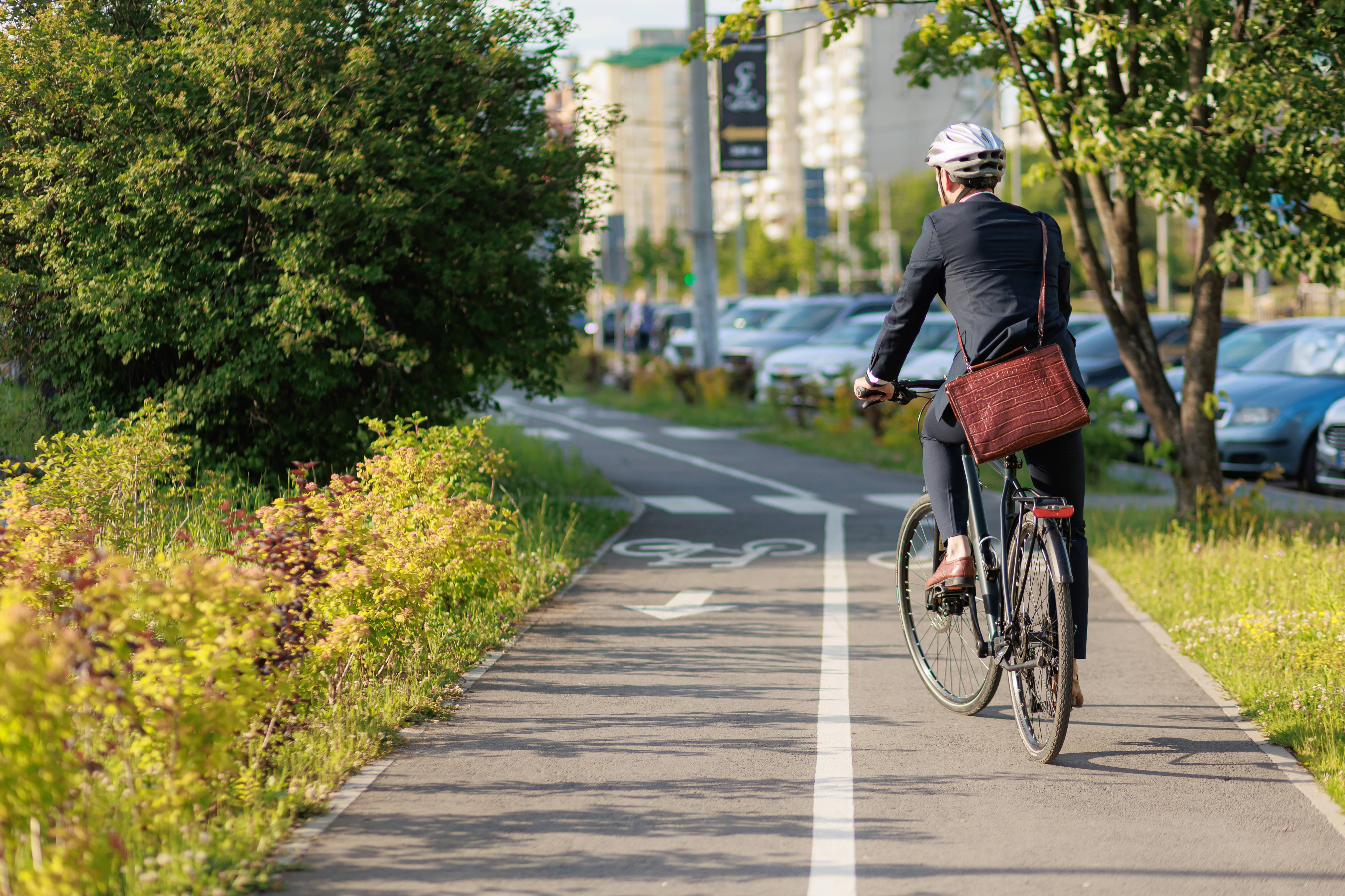 Ein Mann im Anzug steht auf seinem Fahrrad auf einem Fahrradweg in der Stadt.