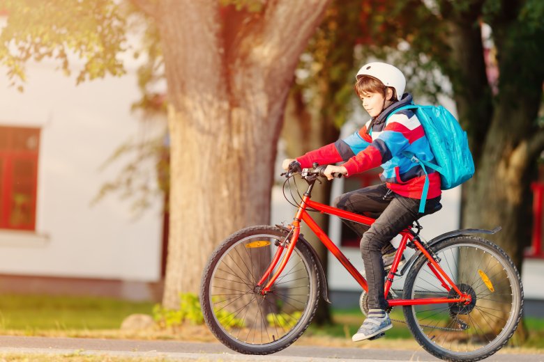 Junge fährt auf rotem Fahrrad im Sommer