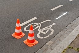 Zwei Pilonen stehen auf der Strasse bei Fahrbahnmarkierungsarbeiten für einen Radweg Zwei Pilonen stehen auf der Strasse bei Fahrbahnmarkierungsarbeiten für einen Radweg