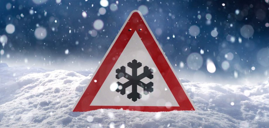 Ausfälle ÖPNV Ein eingeschneites Verkehrsschild, das vor Glätte warnt.