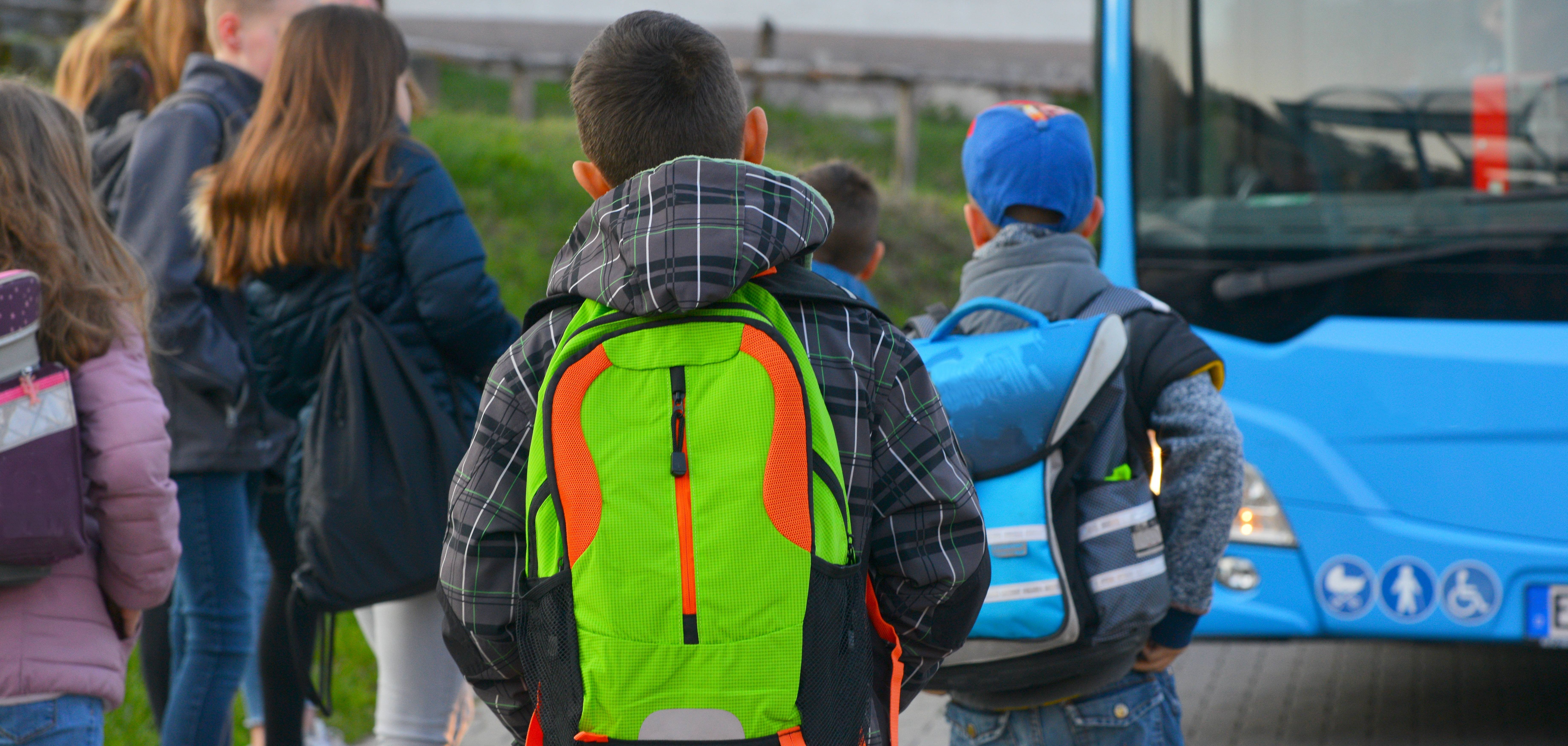 Schüler mit Schulrucksack der Grundschule auf dem morgendlichen Weg zum Schulbus.