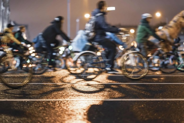 Radfahrer Abends Eine Gruppe Radfahrer, die abends auf der Straße fahren, aber nur verschwommen zu sehen sind.