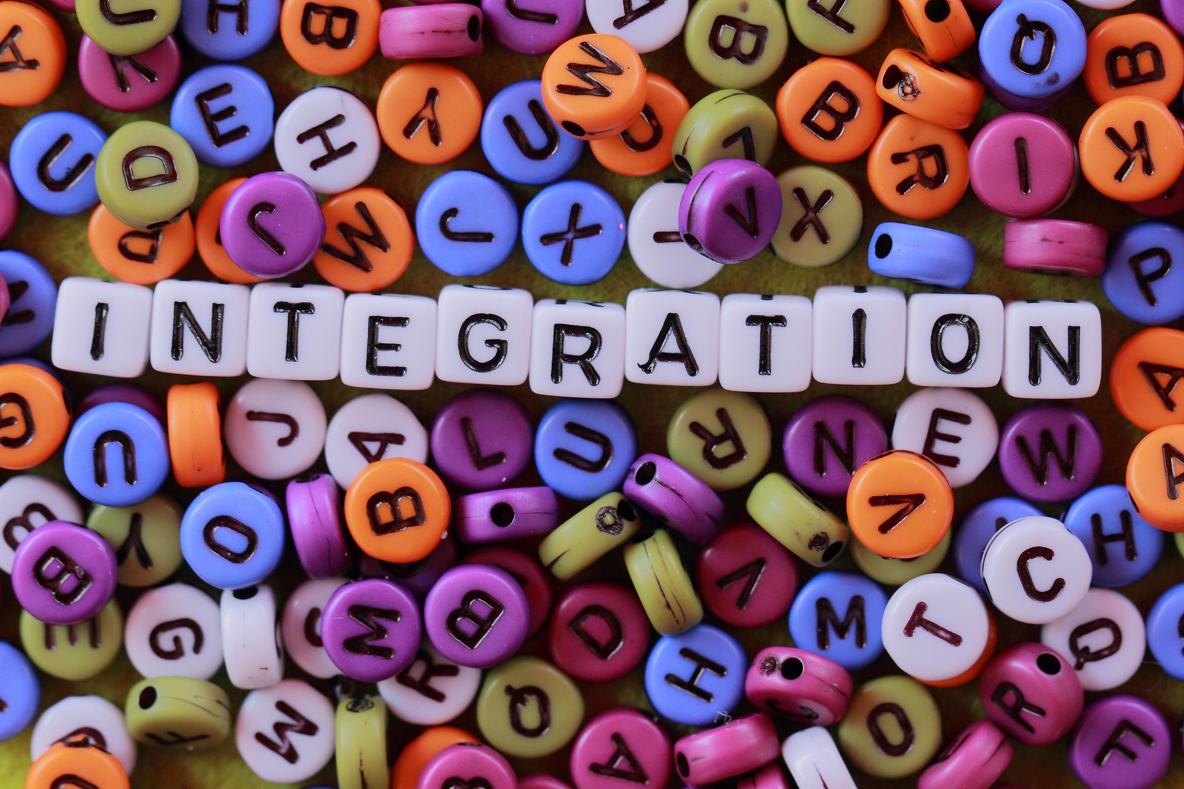 Aus bunten Buchstaben, wie man sie normalerweise zum Beispiel an einer Kette findet, wird das Wort "Integration" gebildet.
