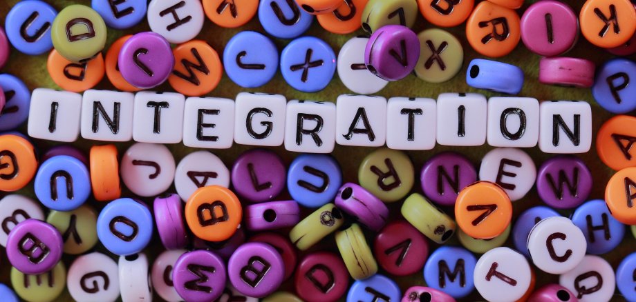 Aus bunten Buchstaben, wie man sie normalerweise zum Beispiel an einer Kette findet, wird das Wort "Integration" gebildet.