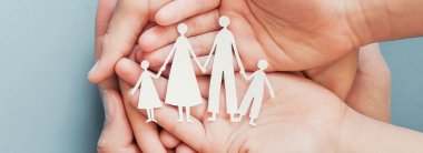 Eltern und Kind halten aus Papier ausgeschnittene Familie in der Hand