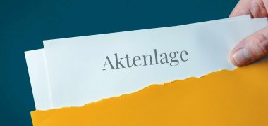 Geöffneter Briefumschlag ,Hand entnimmt Unterlagen mit Überschrift Aktenlage.