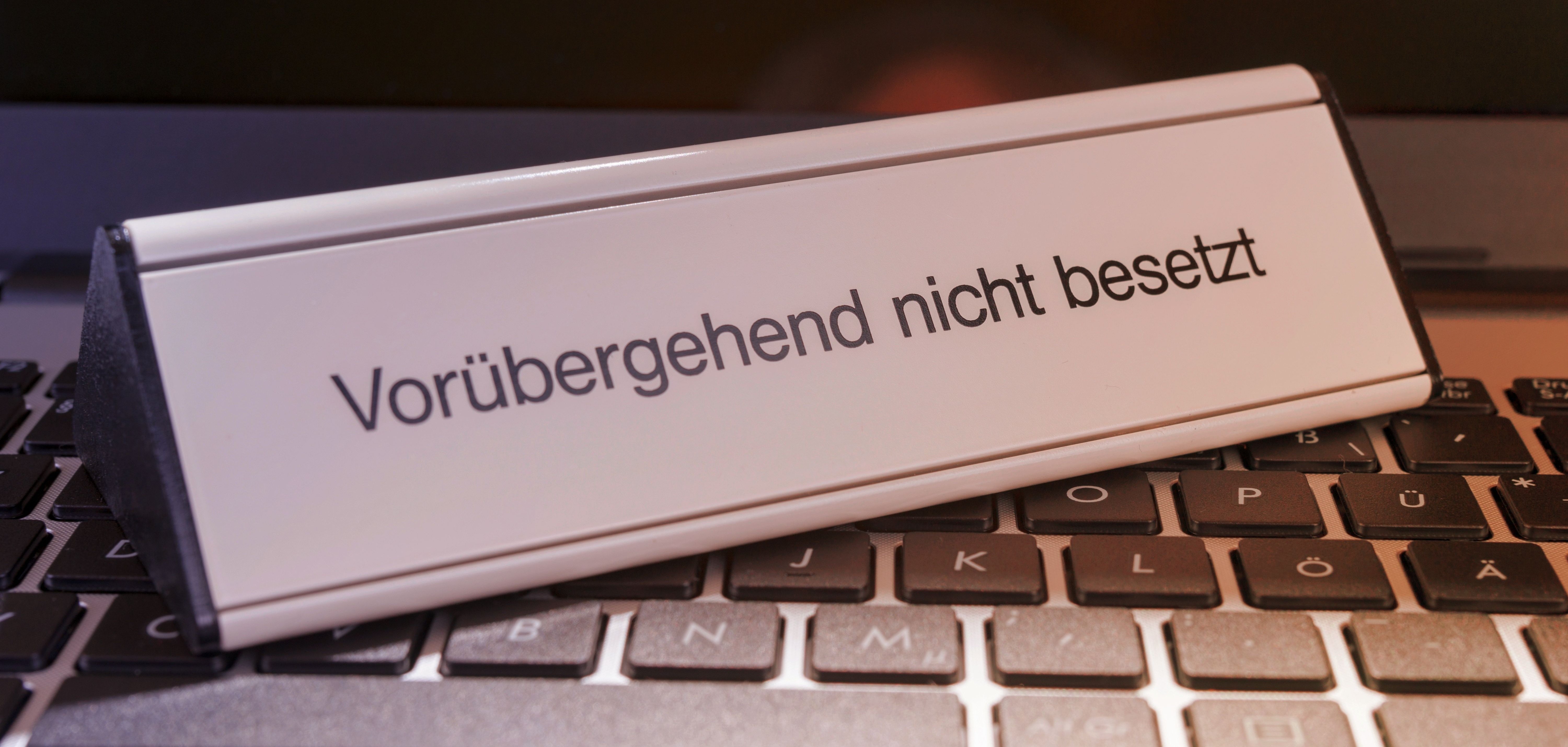 Ein Schild mit der Aufschrift "Vorübergehend nicht besetzt" steht auf einer Computer-Tastatur.