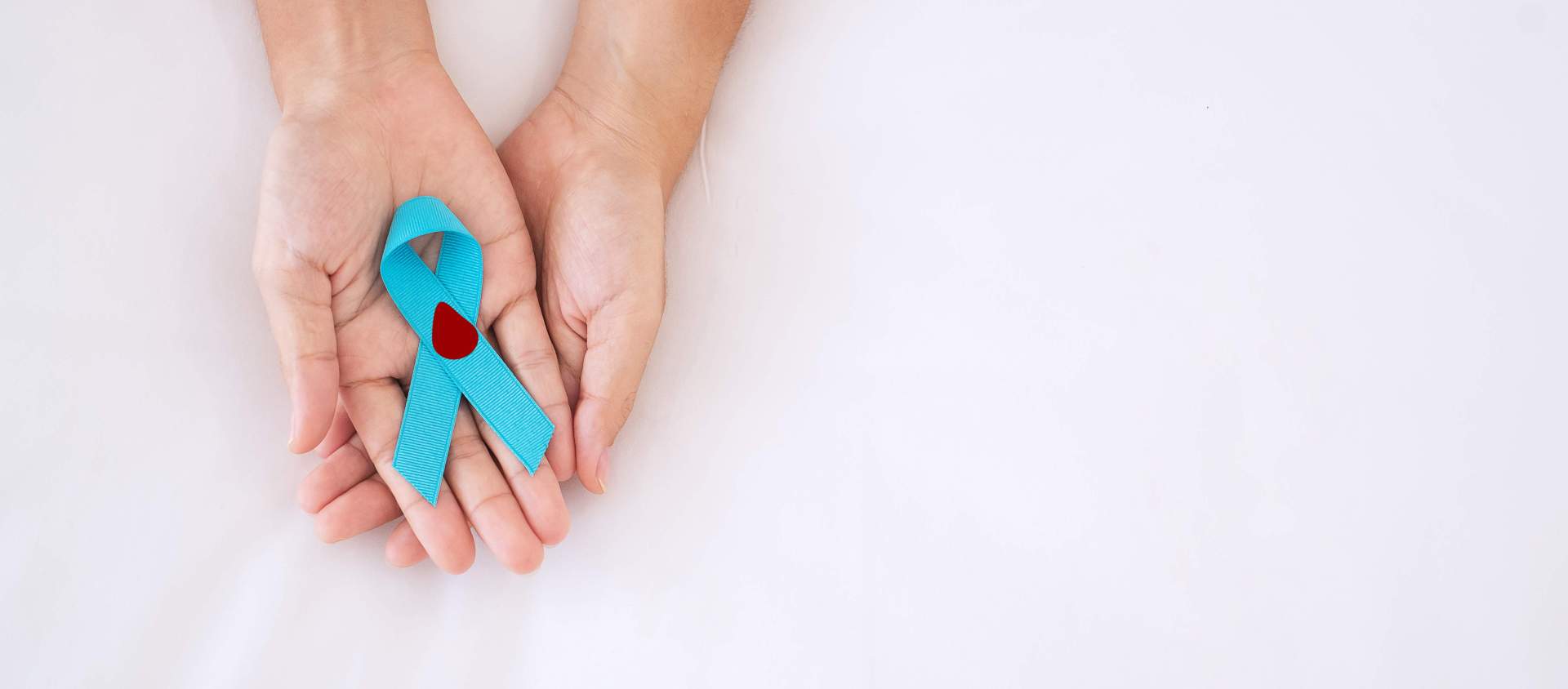 Infoveranstaltung Diabetes Zwei Hände halten eine blaue Schleife, auf der ein Symbol eines Bluttropfens abgebildet ist.