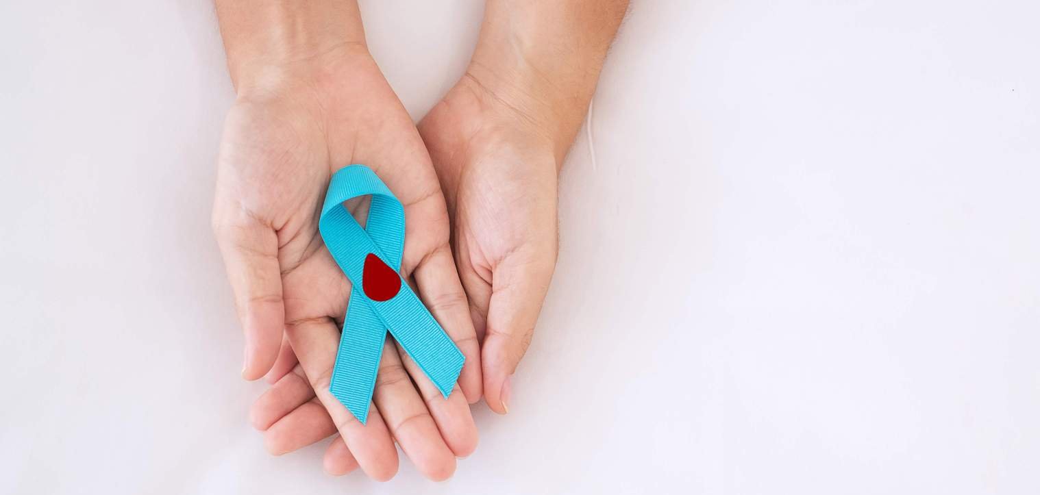 Infoveranstaltung Diabetes Zwei Hände halten eine blaue Schleife, auf der ein Symbol eines Bluttropfens abgebildet ist.