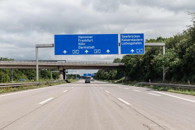 Eine dreispurige Autobahn an einem bewölkten Tag. Über der Straße hängen zwei Schilder. Das eine schildert die A67 Richtung Hannover, Frankfurt, Köln und Darmstadt aus, das andere die A6 Richtung Saarbrücken, Kaiserslautern und Ludwigshafen.