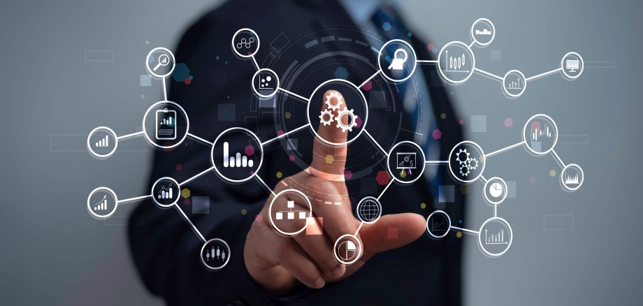 Ein Symbolbild, das die Digitalisierung veranschaulichen soll. Zu sehen ist eine Hand, die verschiedene Symbole, die ähnlich wie ein Hologramm vor ihr schweben, zur Auswahl hat, auf die sie, wie auf einen Touchscreen, drücken kann. Symbolisiert sind zum Beispiel das Internet der Dinge, Automatisierung oder Cloud Computing.