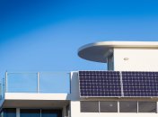 Ein Photovoltaik-Modul ist an einem weißen Hausbalkon angebracht.