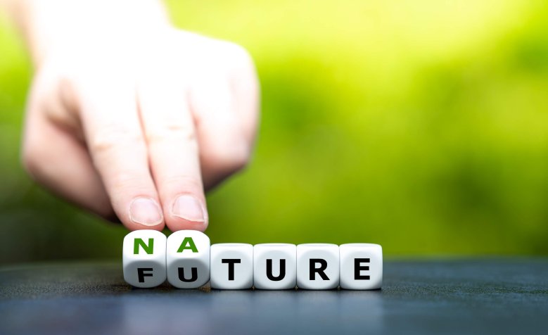 Nature / Future Würfel mit Buchstaben, bei denen die ersten beiden durch eine Hand auf der Kippe gehalten werden. So entsteht gleichzeitig das Wort "Nature" und "Future".