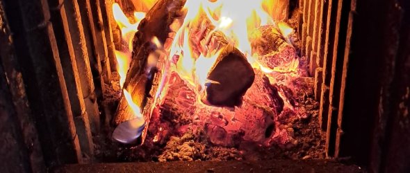 Ein Feuer lodert hinter der Glasscheibe eines Kachelofens.