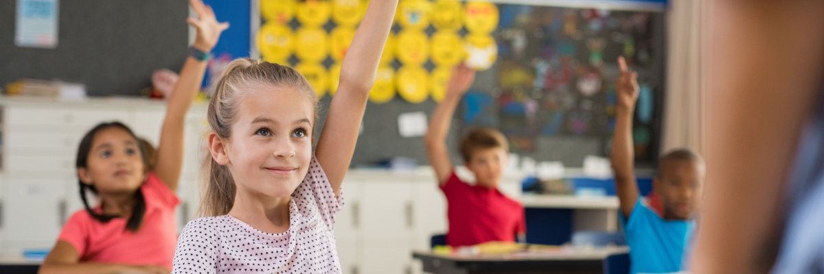 Children raising hands in classroom