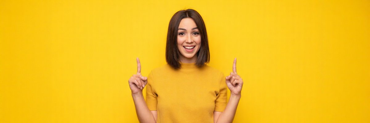 Pretty young asian woman in white t-shirt, showing thumbs up and smiling, praise good offer, recommend product, standing satisfied over yellow background
