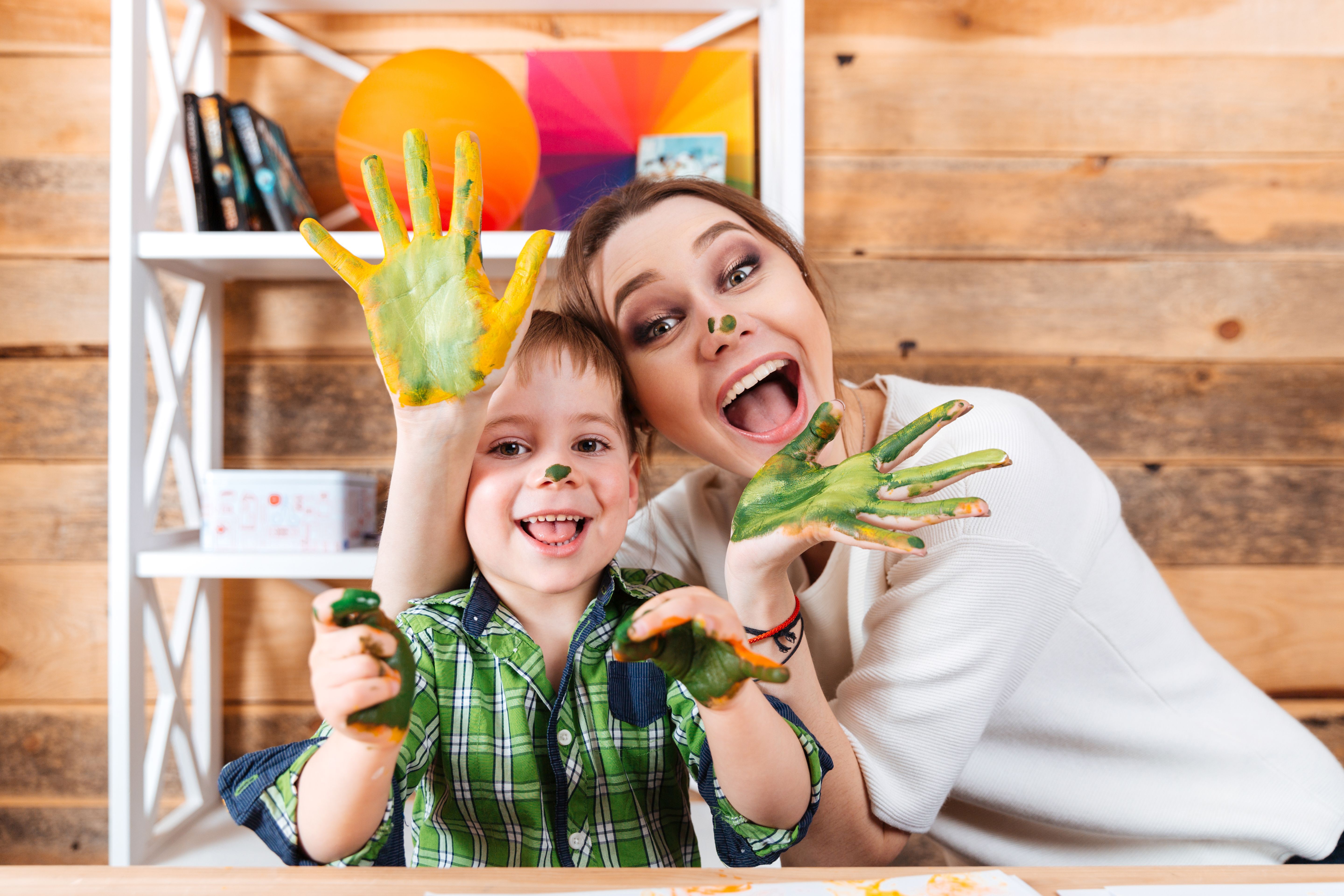 Cheerful mother and son with painted hands having fun together