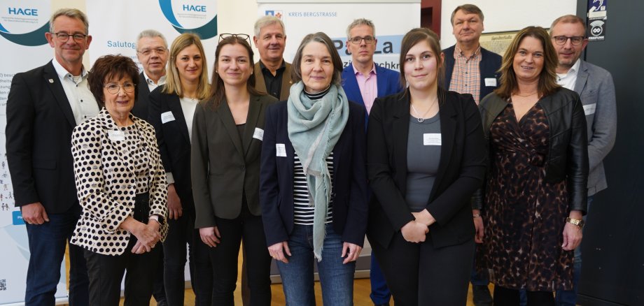 Gruppenbild NORIE-Akteurinnen und Akteure Landrat Christian Engelhardt und die Erste Kreisbeigeordnete Angelika Beckenbach stehen mit den Akteurinnen sowie Kooperationspartnerinnen und -partnern des NORIE-Projektes, das die Kommunen Biblis, Bürstadt, Einhausen, Groß-Rohrheim, Lampertheim und Lorsch umfasste, bei der Abschlussveranstaltung vor NORIE-Bannern.