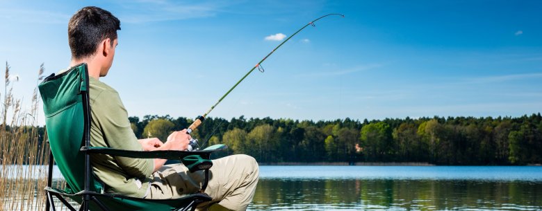 Mann sitz am Steg und fischt