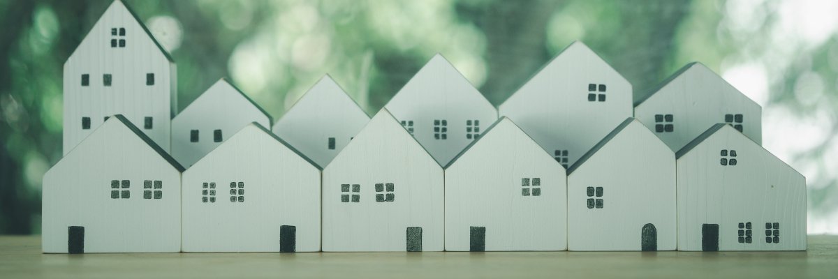 White houses different size arranged in a row on table against nature background. kleine Holzhäuser Modelle vor einem Naturhintergrund